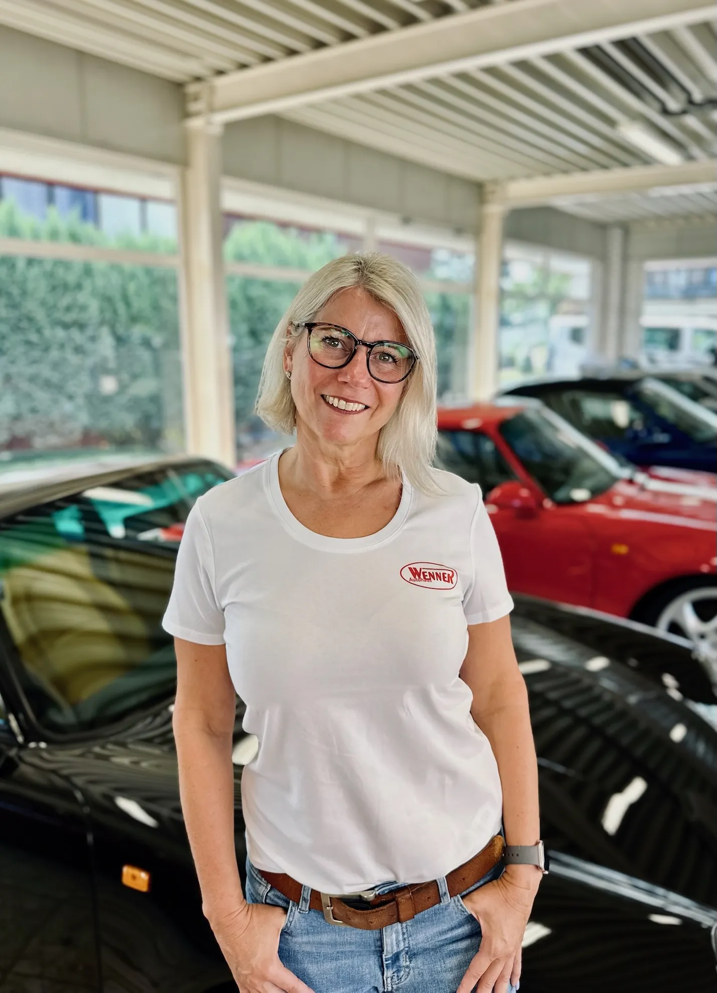 Blonde Mitarbeiterin des Autohauses Wenner mit Brille im weißen Hemd